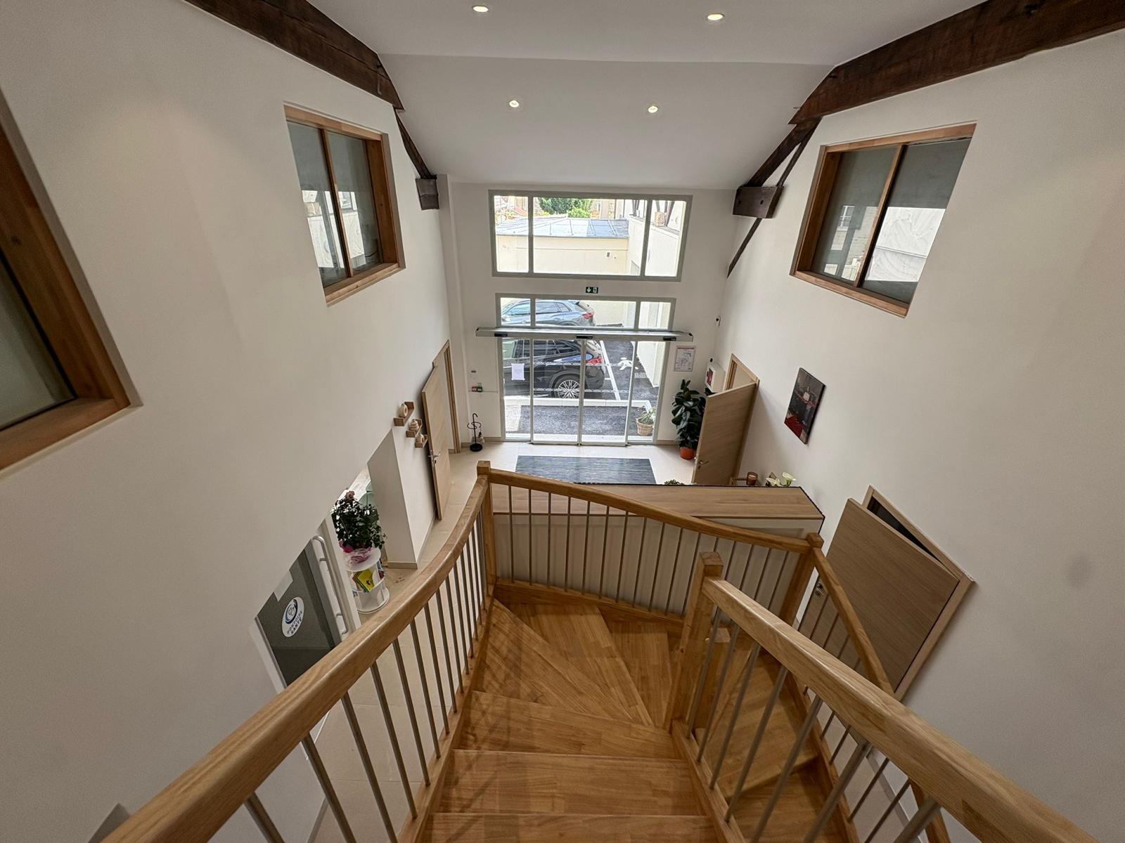 Hall d'accueil et escalier en bois menant aux étages
